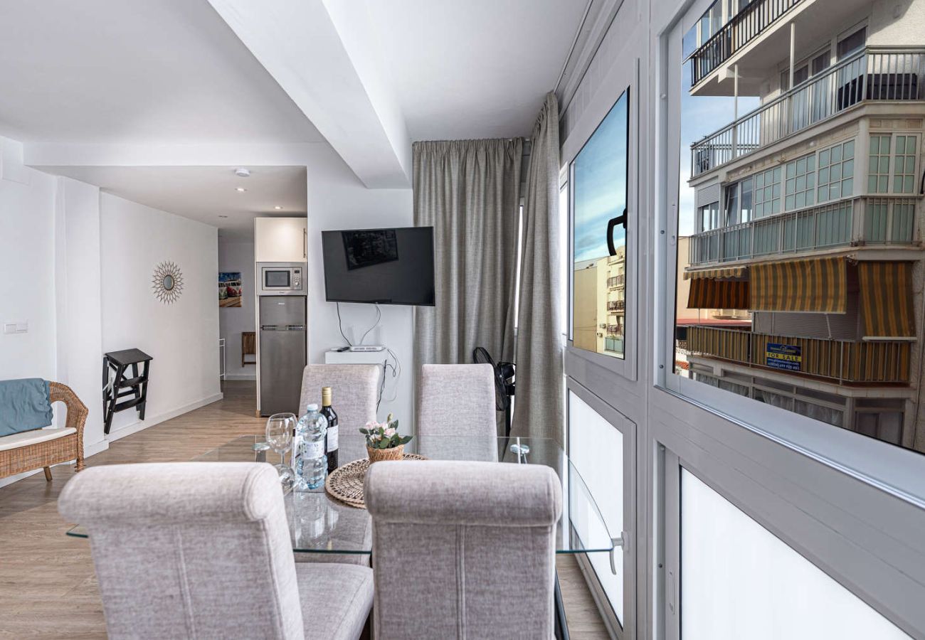 Coin repas avec table en verre à côté d'une grande fenêtre lumineuse à Nerja.