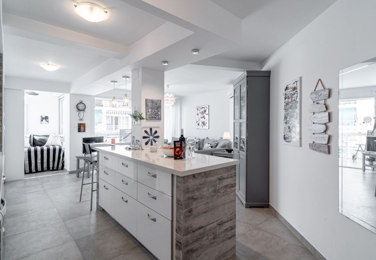 Coin repas avec table en bois et chaises design à côté de la cuisine équipée à Nerja.
