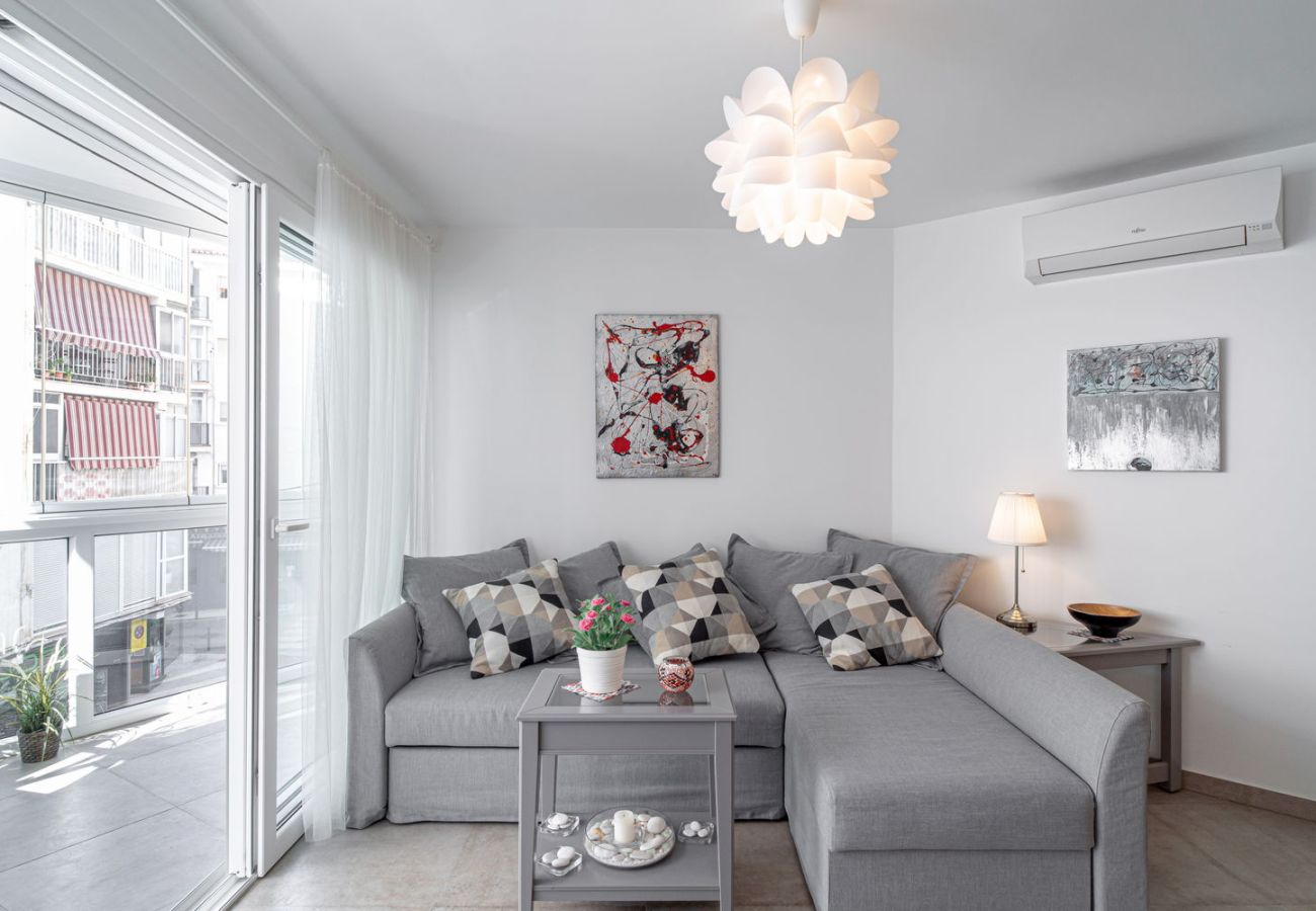 Salon lumineux avec canapé design et accès direct au balcon vitré dans le centre de Nerja.