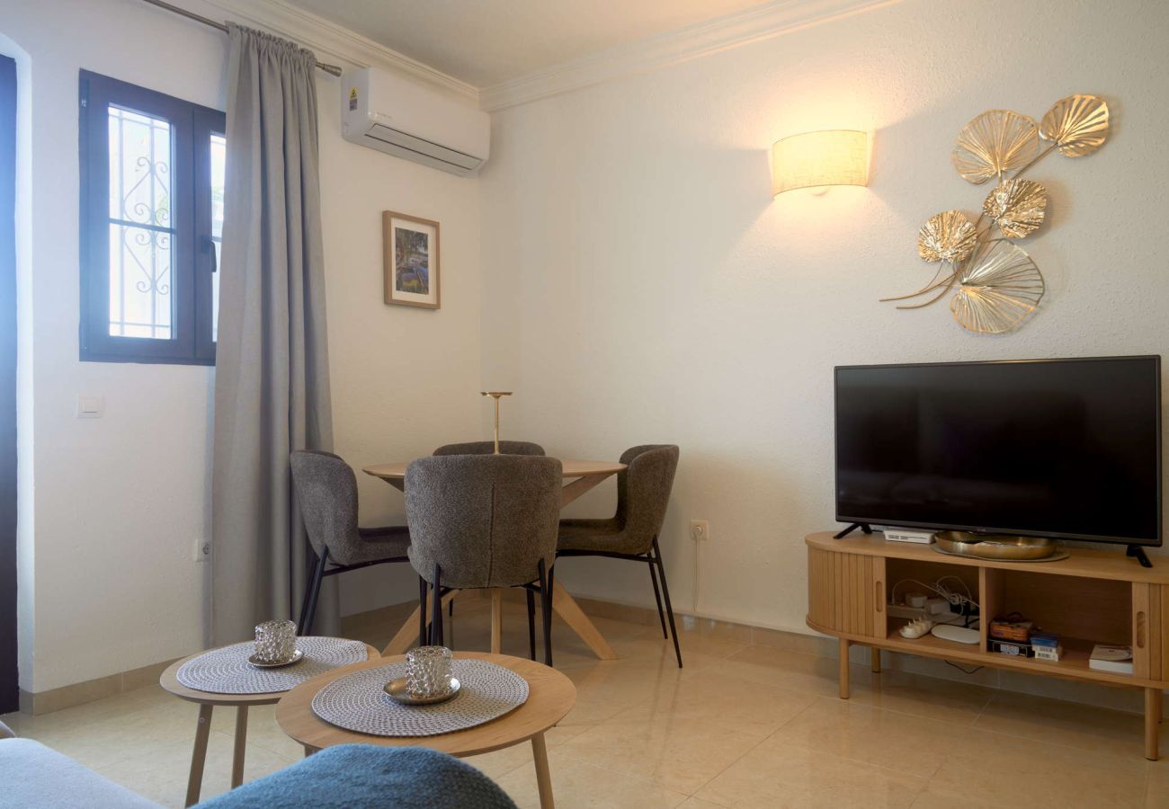 Intérieur lumineux du salon-salle à manger avec accès à la terrasse à Capistrano Village Nerja.